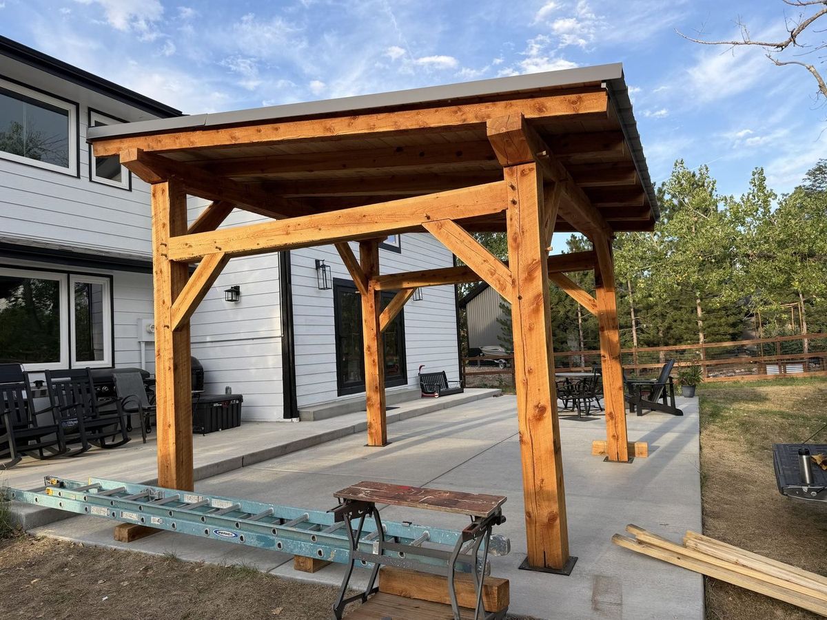 Completed timber frame pavilion at sunset behind a family home in Arvada, Colorado