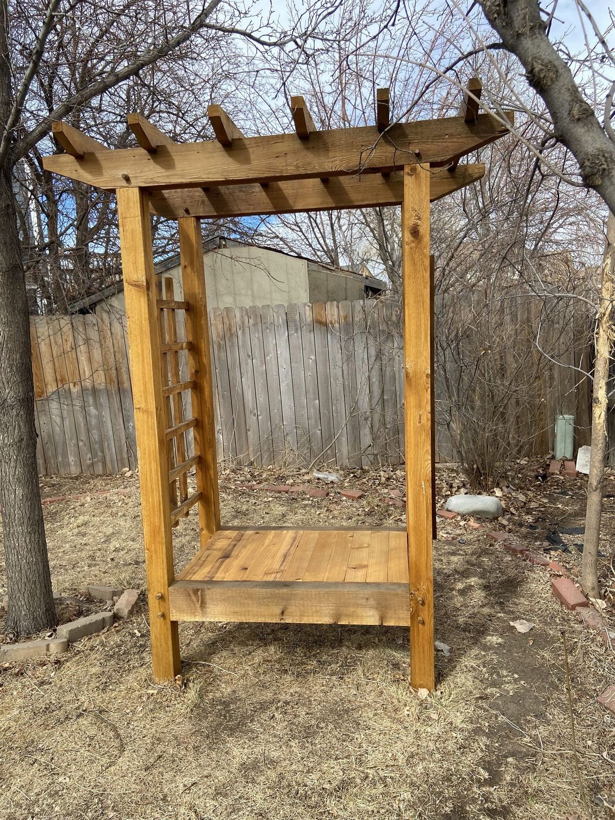 Freestanding cedar trellis panel with ladder-style lattice standing in front of a fence