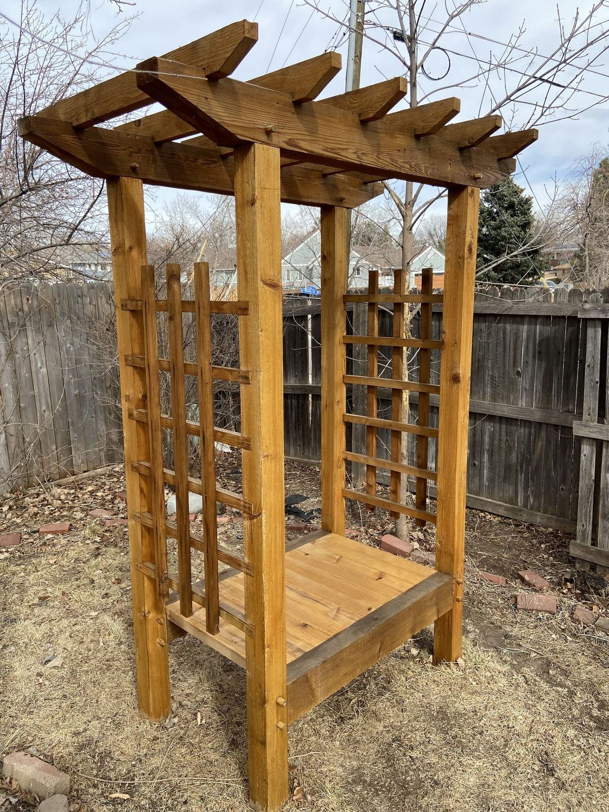 Front view of a complete cedar trellis with posts, lattice and bench built as one piece