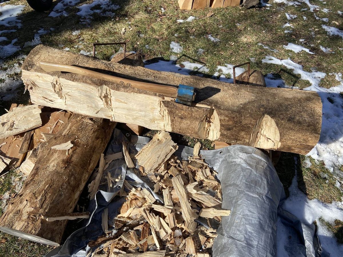 A pile of fresh wood chips on the ground around a log being hand-hewn