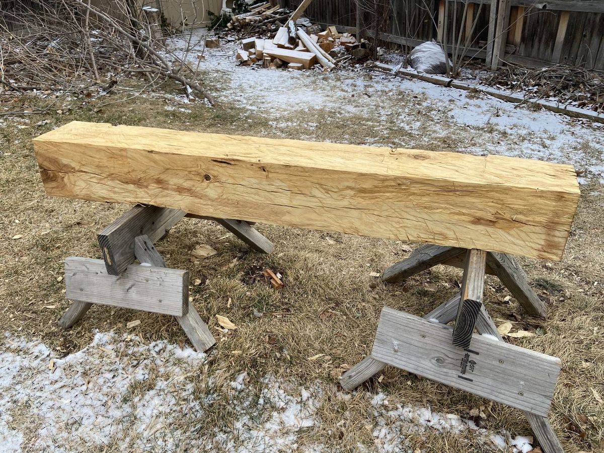 A freshly hewn pale beam on sawhorses with axe marks showing along its face