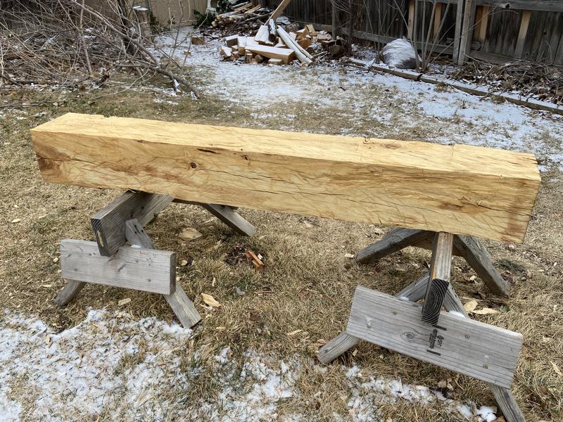 Hand-hewn beam on sawhorses showing broadaxe texture