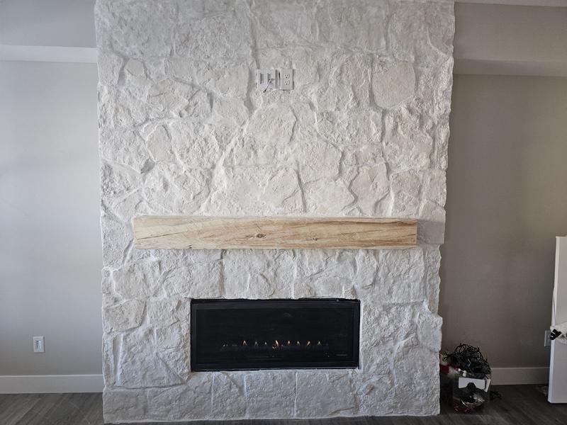 Hand-hewn timber fireplace mantel installed over modern fireplace